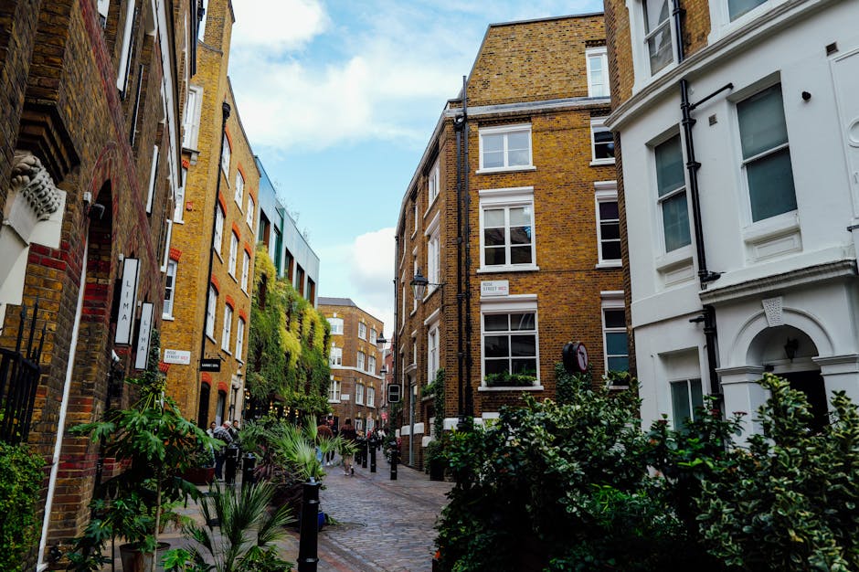 A narrow cobblestone street in Wapping High Street lined with multi-storey brick and white-painted residential buildings. The buildings feature large sash windows, some with white frames and flower bo